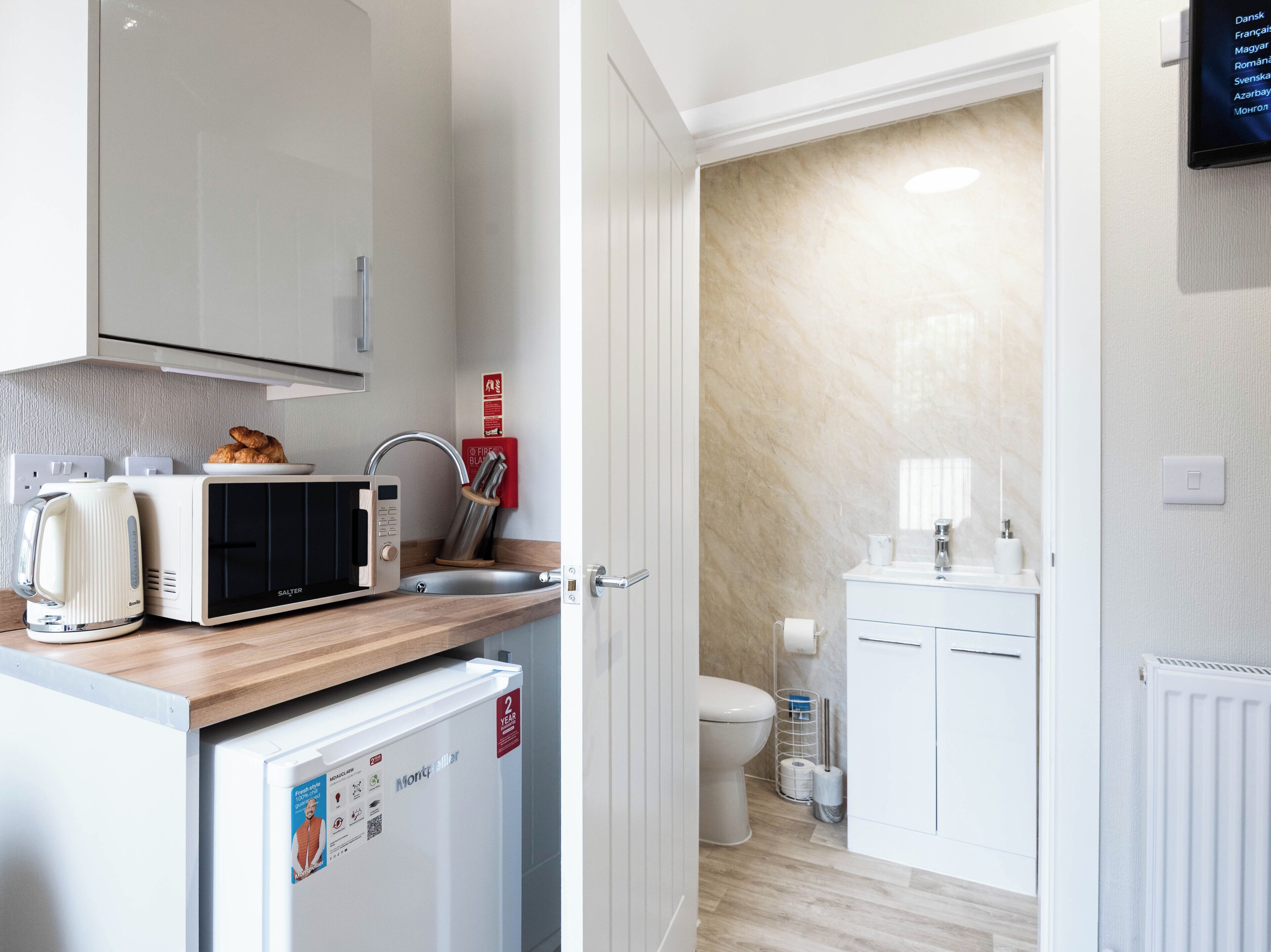 Una kitchenette compacta equipada con microondas, tostadora y refrigerador pequeño.