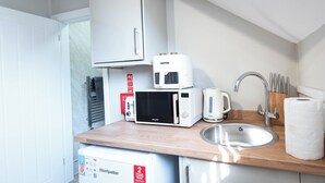 A compact kitchenette with a microwave, toaster, and a small refrigerator. - The Wire B4 by Guestz (Warrington)