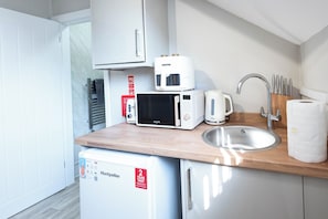 Une petite cuisine équipée d’un four à micro-ondes, d’un grille-pain et d’un petit réfrigérateur.