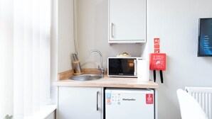 A compact kitchenette with a sink, a microwave, and a small refrigerator. - The Wire B4 by Guestz (Warrington)
