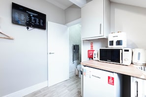 Une cuisine moderne équipée d’un four à micro-ondes, d’un grille-pain et d’un petit réfrigérateur. Un écran numérique affiche un menu de sélection des langues.