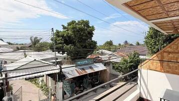 A balcony with a view of a train station and a building with a thatched roof.