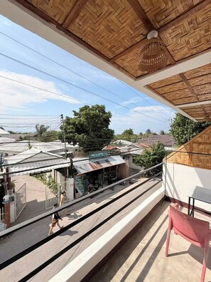 Un balcón con vistas a una estación de tren y un edificio con techo de paja.
