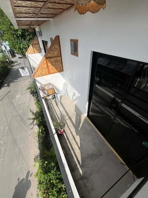 A building with a white exterior, a black garage door, and a covered outdoor area with a bench and potted plants. - Marz inn Moalboal (Moalboal)