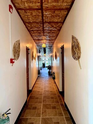 Un pasillo con suelo de baldosas, techo de madera y paredes decoradas con adornos.