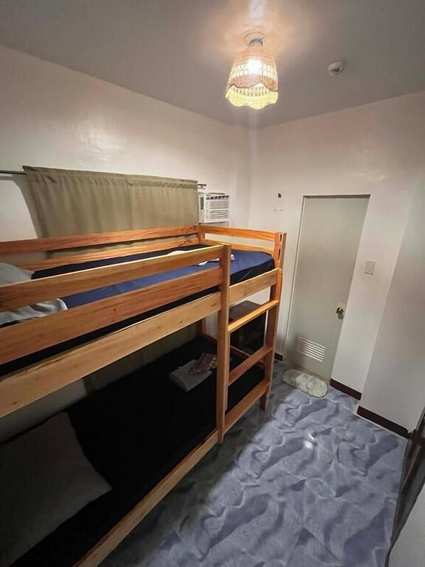 A bunk bed with a wooden frame and a mattress, a door, and a ceiling light fixture. - Marz inn Moalboal (Moalboal)