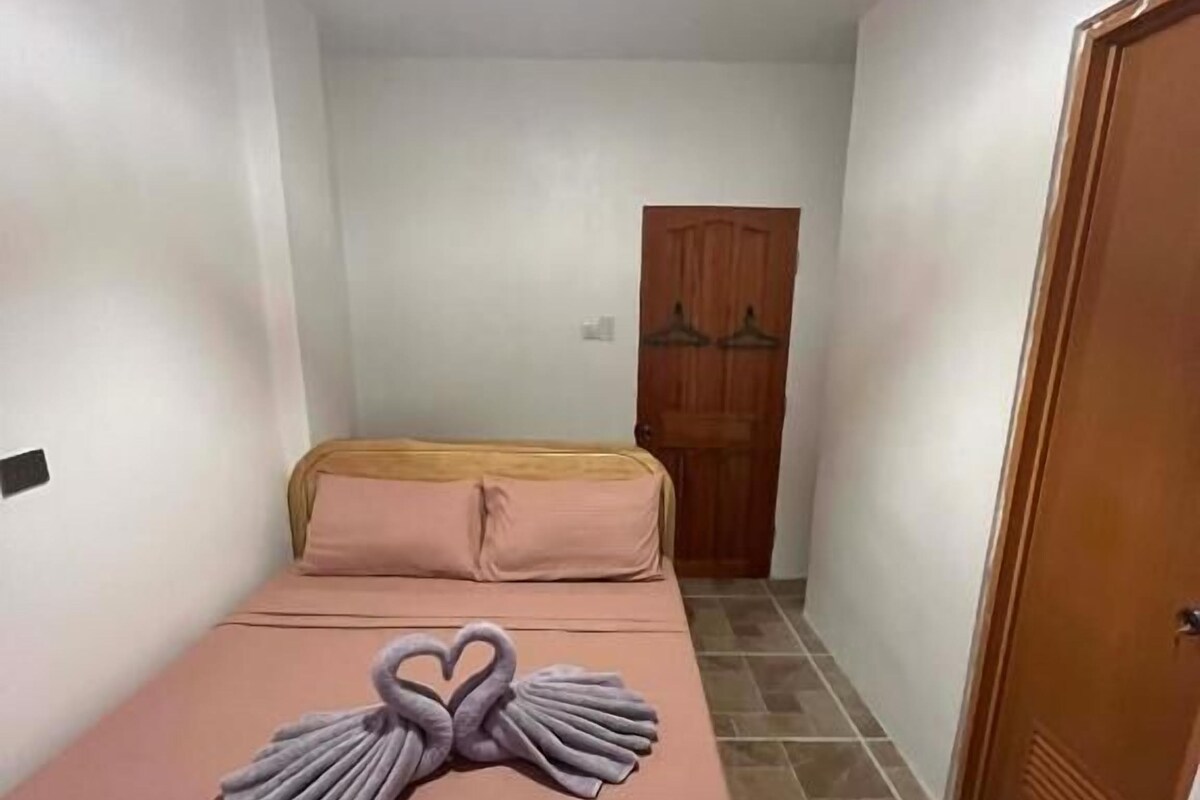 A room with a bed, a wooden door, and a chandelier.