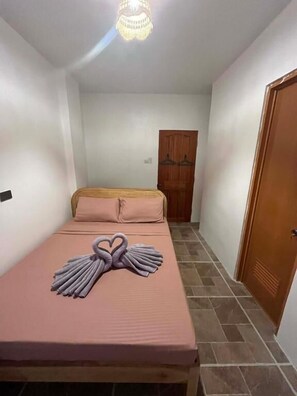 Una habitación con una cama, una puerta de madera y una araña.