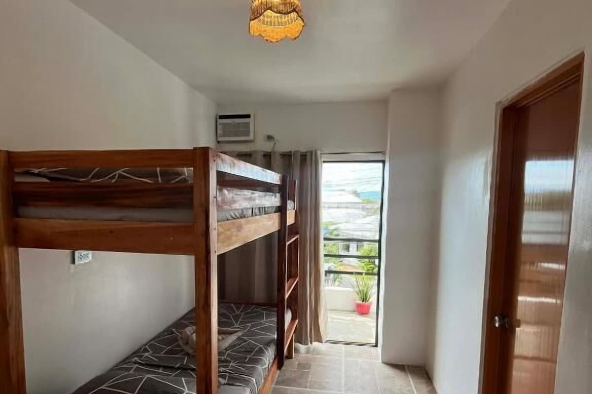 A corridor with bunk beds, a ceiling light, and a door leading to an outdoor area.