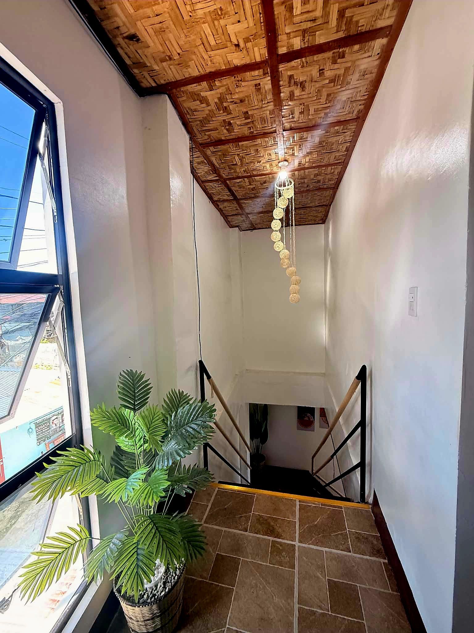 A staircase with a wooden ceiling and a hanging light fixture.