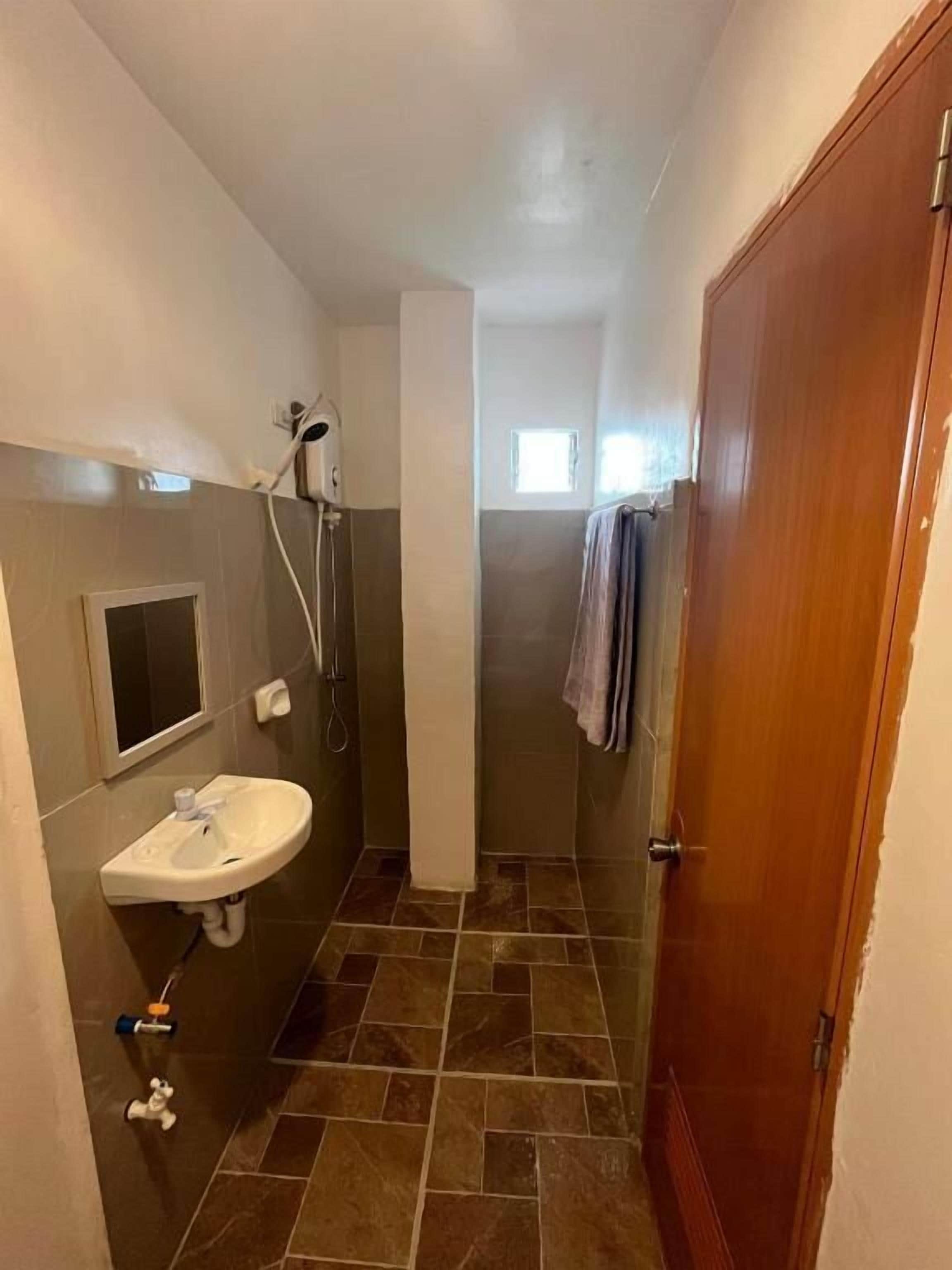 Ein Badezimmer mit Waschbecken, Dusche und einer Holztür.