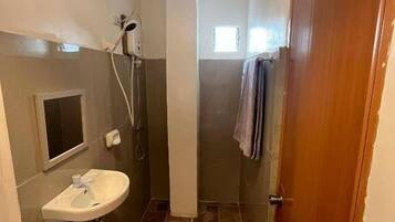 Ein Badezimmer mit Waschbecken, Dusche und einer Holztür.