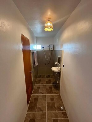 A narrow hallway leading to a bathroom with a shower, a sink, and a ceiling light fixture. - Marz inn Moalboal (Moalboal)