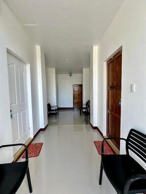 A hallway with a door on the left, a bench on the right, and a table with chairs in the background. - Marz inn Moalboal (Moalboal)