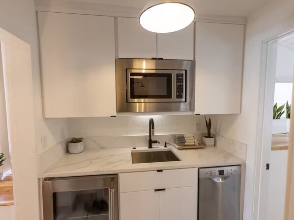A modern kitchen with white cabinetry, a stainless steel microwave, a built-in oven, and a dishwasher.