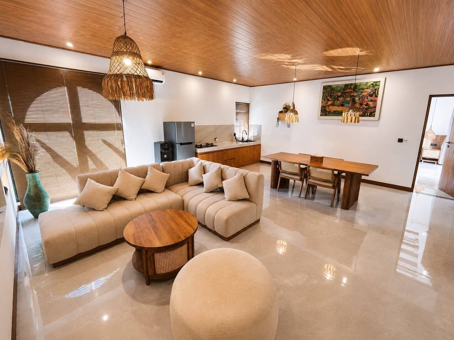A modern living room with a sectional sofa, a wooden dining table, and a round coffee table.