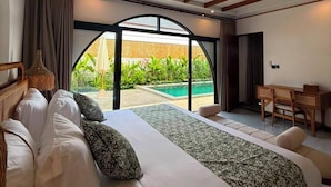Ein Schlafzimmer mit einem großen Bett, einem Schreibtisch und Blick auf ein Schwimmbad.