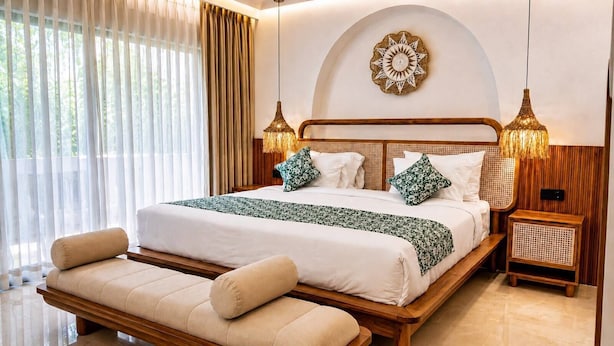 Ein helles Schlafzimmer mit einem großen Bett, Nachttischen, einer Bank und einer Wanddekoration.