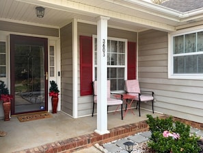 A covered porch with a door, two windows with shutters, and a column with a number.