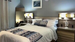 Una habitación de hotel con una cama grande, lámparas de noche, un espejo y una obra de arte colgada en la pared.