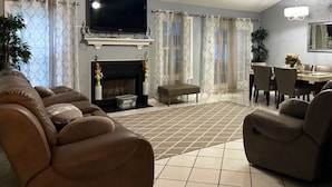 Una sala de estar con chimenea, televisión y comedor con sillas y mesa.