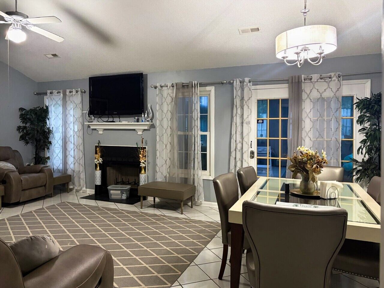 Una sala de estar con chimenea, televisor y comedor con sillas y mesa.