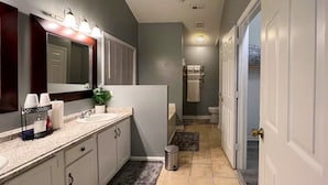 Un baño moderno con tocador, lavamanos y espejo.