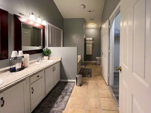 Un baño moderno con tocador, lavamanos y espejo.