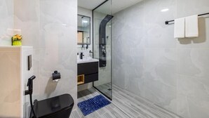 Une salle de bain moderne avec une douche à l’italienne en verre, des toilettes noires et un tapis bleu.