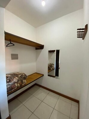 A small room with a bunk bed, a mirror, and a wooden shelf.