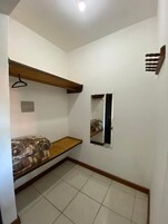 Quarto pequeno com beliche, espelho e prateleira de madeira.