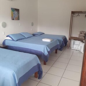 A hotel room with two beds, a small table, a mirror, and a shelf with bags. - HOTEL SOL A SOL (Cananéia)