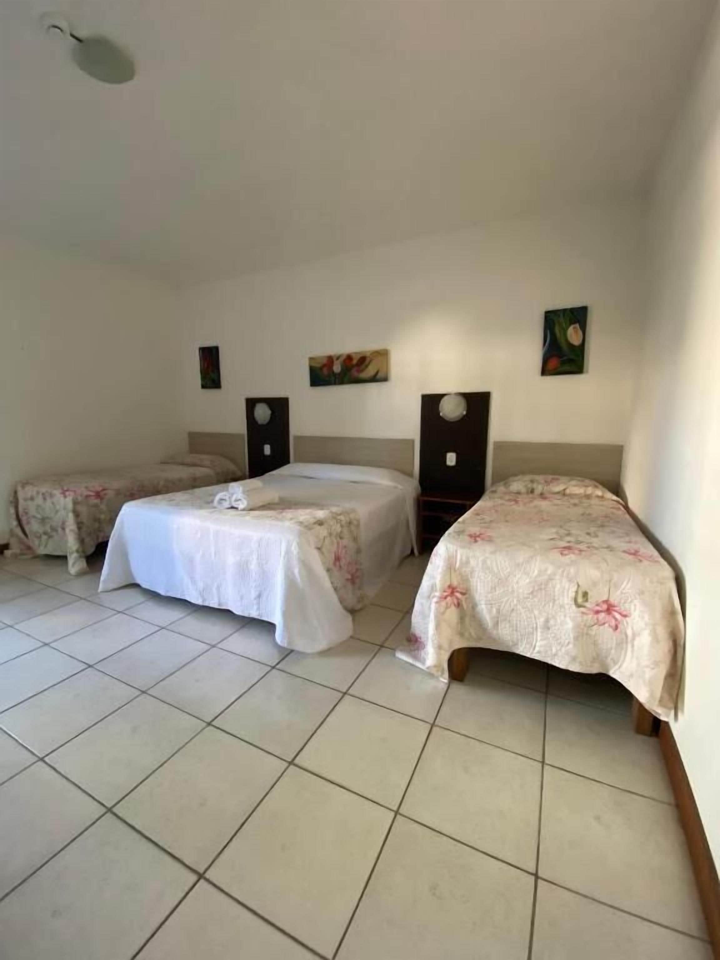A hotel room with two beds, a small table, and a wall-mounted speaker.