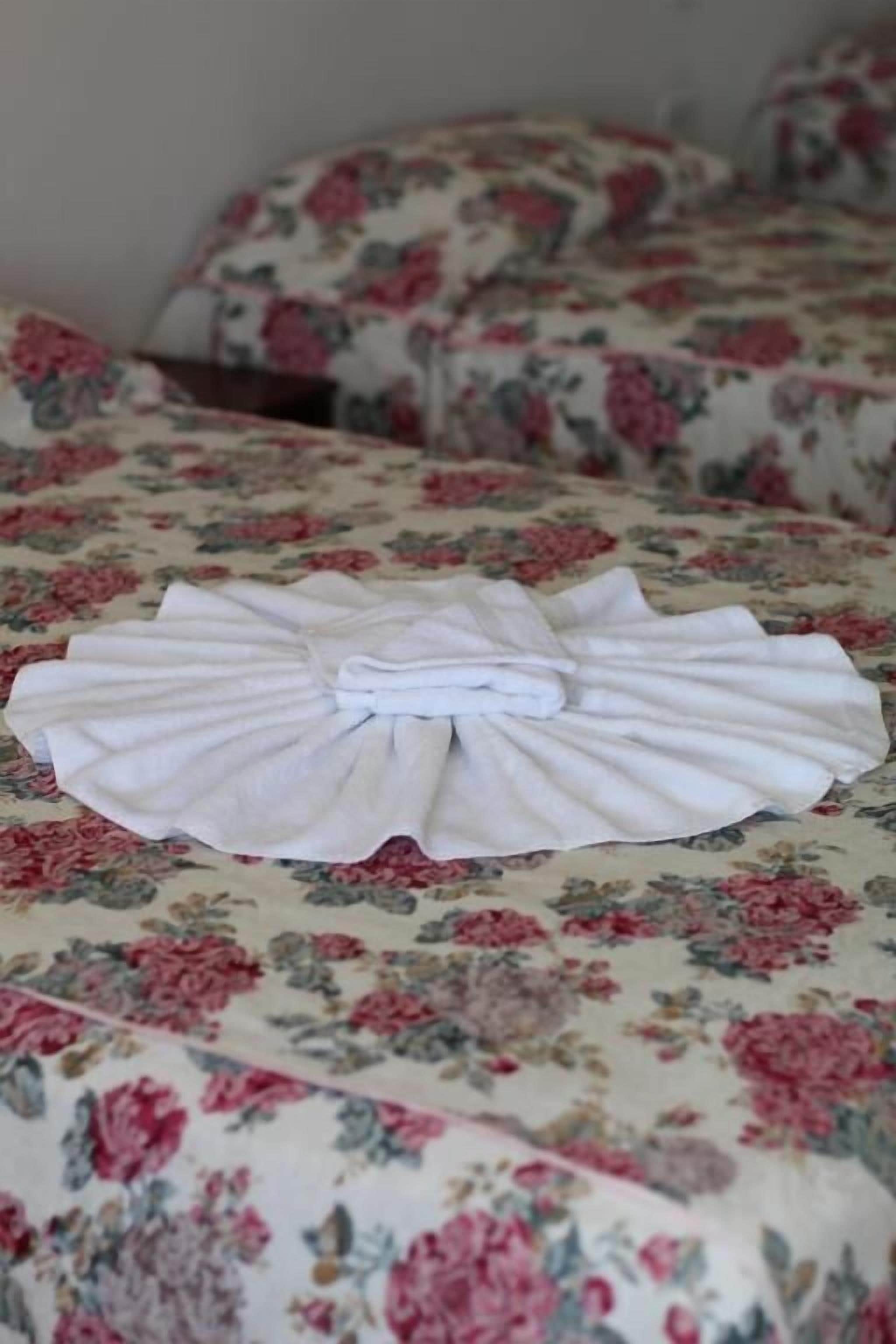 Una toalla blanca doblada con cuidado sobre una colcha estampada con motivos florales.