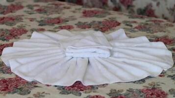 Una toalla blanca doblada con cuidado sobre una colcha estampada con motivos florales.