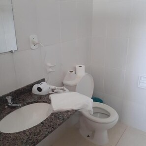 A bathroom with a sink, toilet, and a hairdryer on the counter. - HOTEL SOL A SOL (Cananéia)