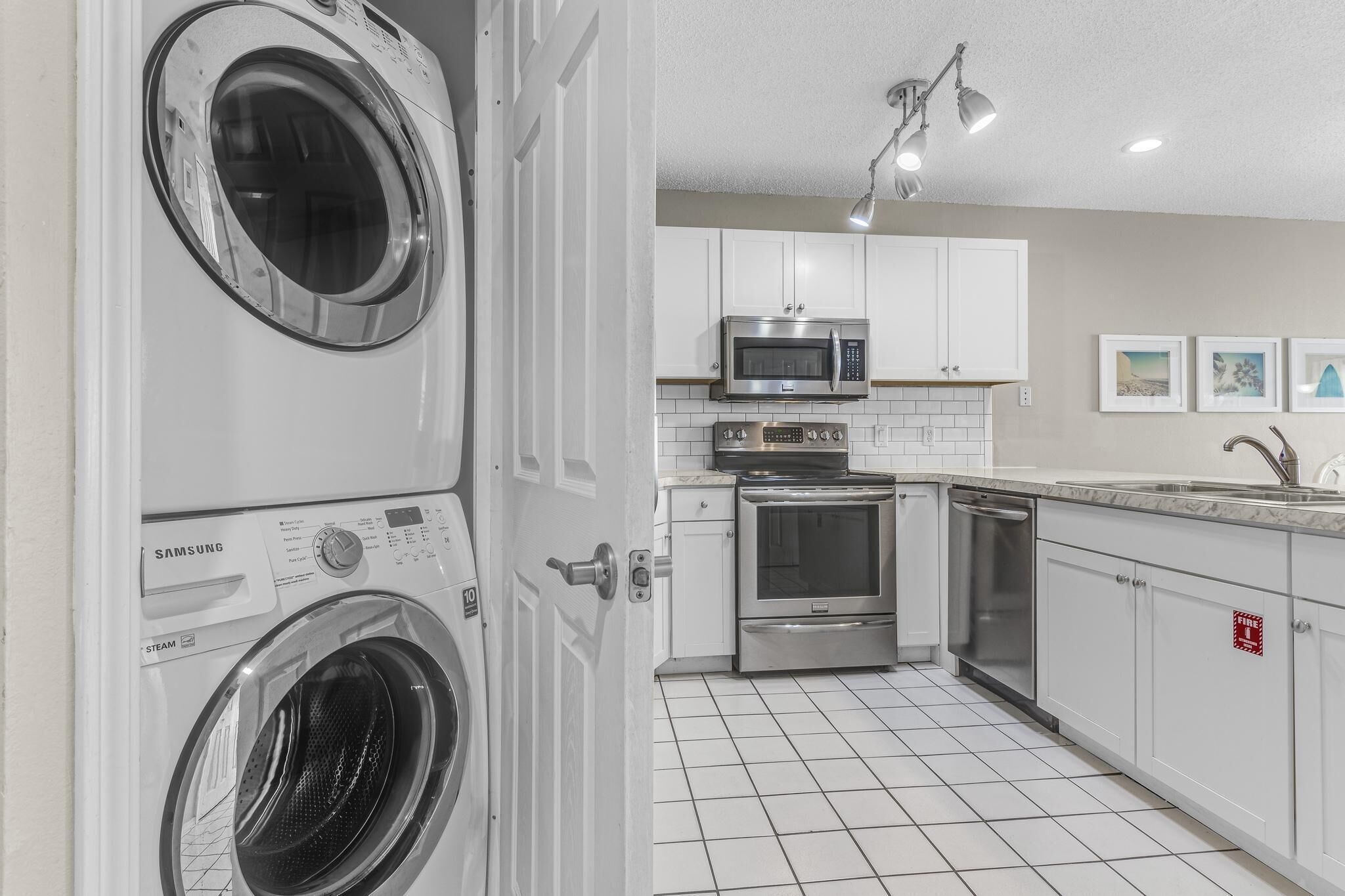 A laundry room with a front-loading washer and dryer, a microwave, oven, and dishwasher in the adjacent kitchen area.