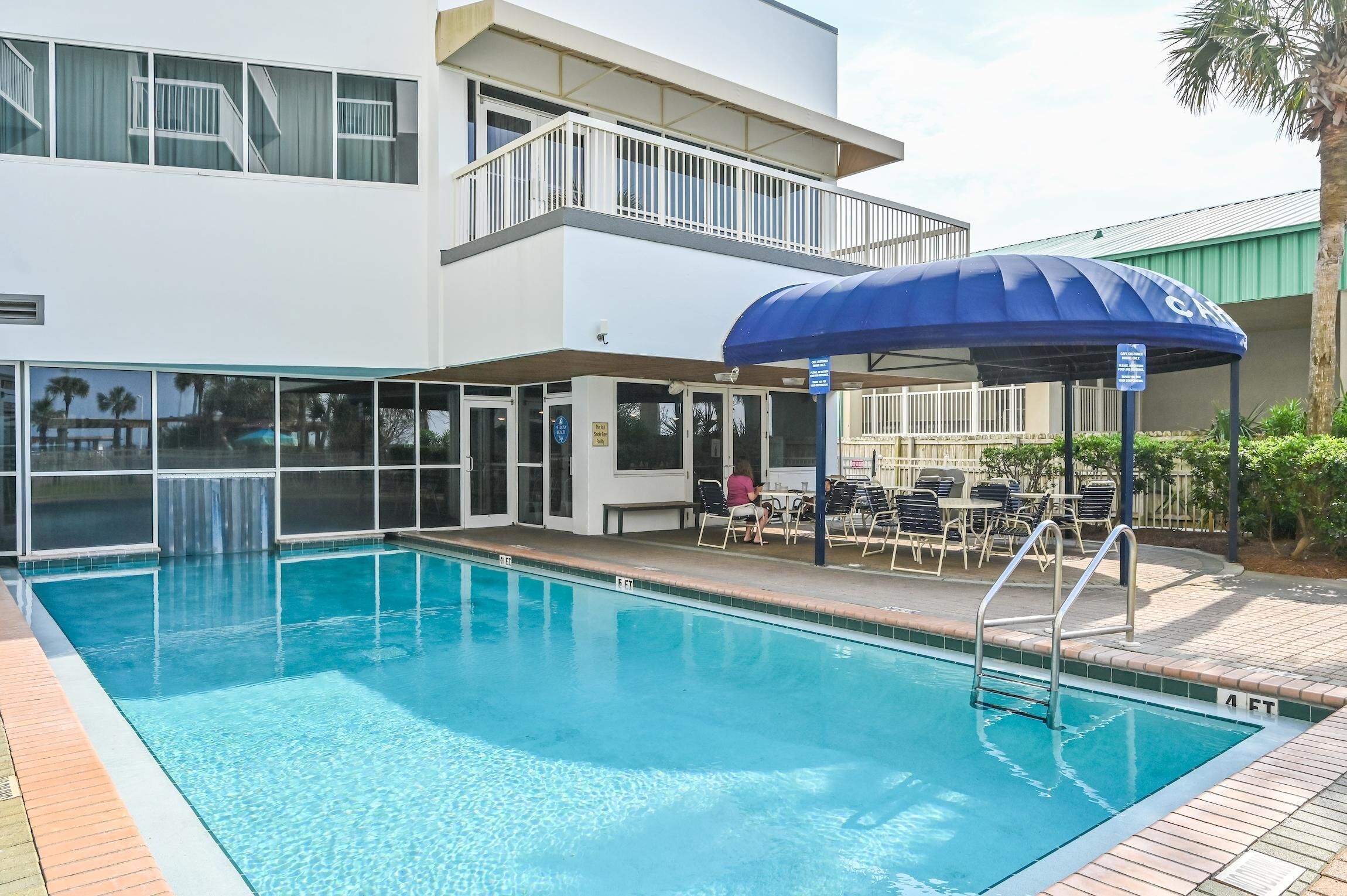 Une piscine dotée d’un espace de repos couvert et d’un bâtiment à deux étages avec des balcons.