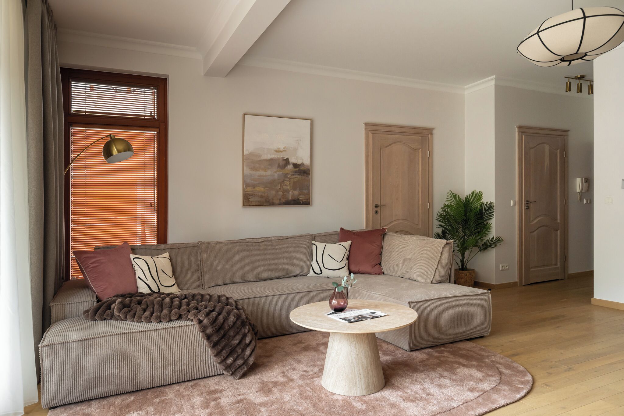 A living room with a sofa, a coffee table, a plant, and a painting on the wall.