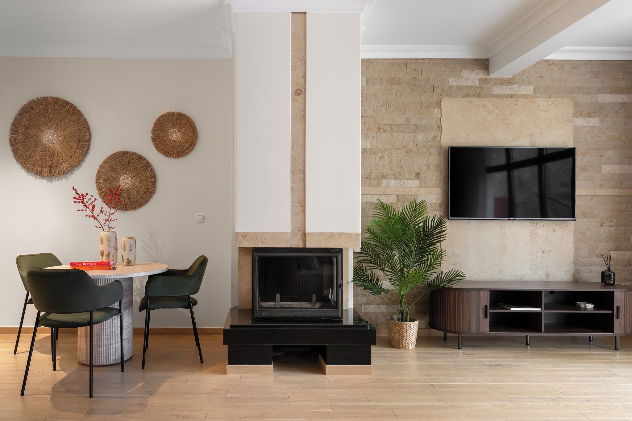 Un salon moderne doté d’une cheminée, d’un téléviseur à écran plat fixé au mur et d’un coin repas avec des chaises et une table.