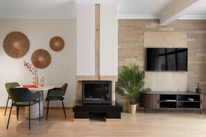 Uma sala de estar moderna com lareira, televisão de tela plana na parede e um espaço de jantar com cadeiras e mesa.