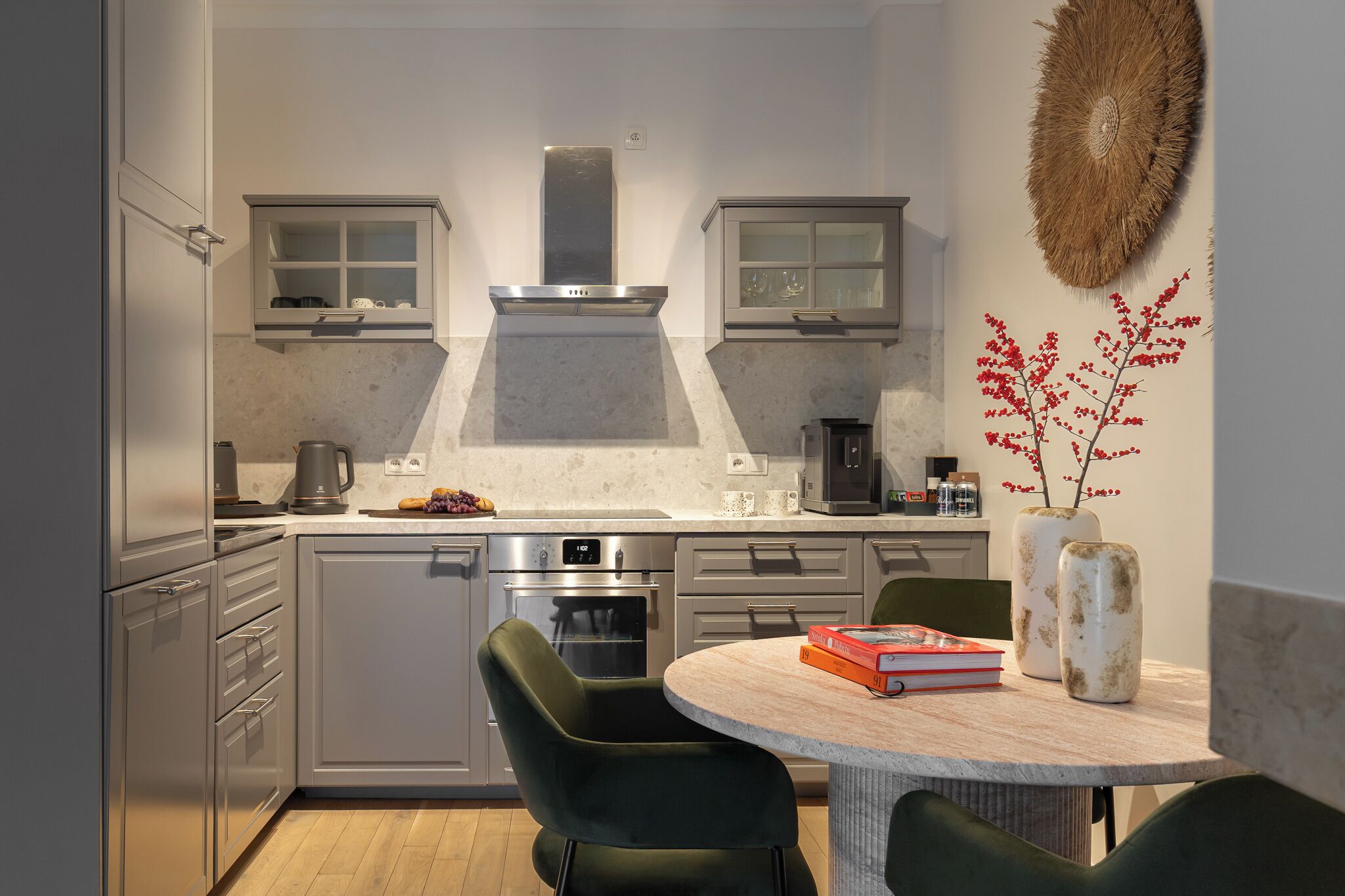 A modern kitchen with a central island, stainless steel appliances, and a dining area with green chairs.