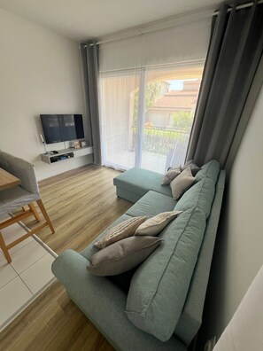 Ein modernes Wohnzimmer mit einer Couch, einem Fernseher und einem Essbereich.