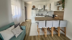 Cozinha moderna com ilha central, banquetas, micro-ondas e geladeira.