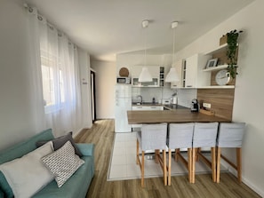 Een moderne keuken met een centraal kookeiland, barkrukken, een magnetron en een koelkast.