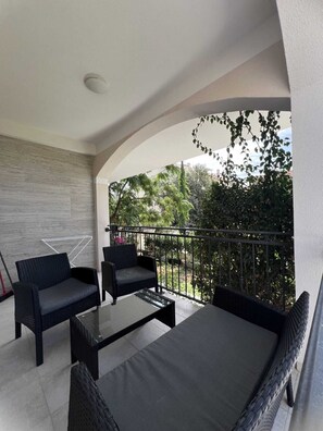 A balcony with two wicker sofas, a glass coffee table, and a view of greenery. - Superb 2-bedroom apartment with AC in charming Bibinje 25 meters from Sea (Bibinje)