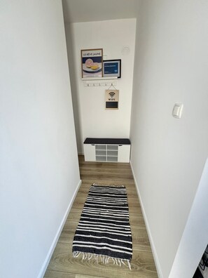 A narrow hallway with a black and white striped rug, a white storage unit, and a framed picture of a citrus fruit. - Superb 2-bedroom apartment with AC in charming Bibinje 25 meters from Sea (Bibinje)