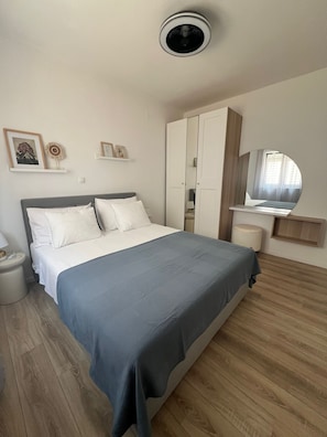 Een slaapkamer met een bed, een kledingkast, een televisie en een kleine tafel.