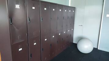 A row of brown lockers with numbered labels, a white exercise ball, and a door with a sign above it.