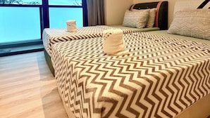 Un lit recouvert d’une couvre-lit à motifs, une fenêtre donnant sur un beau paysage et un canapé agrémenté de coussins.